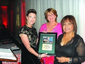 GFWC Coral Gables Woman’s Club president Mireya Kilmon (left) poses with award to be presented to the HealthFoundation of South Florida with club member Susie Tilson (center) and Dental Clnic director Dr. Iris Torres.