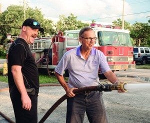 Cory Hogan shows Bill Quesenberry how to use fire hose, one of many crazy things attendees can do at car show.