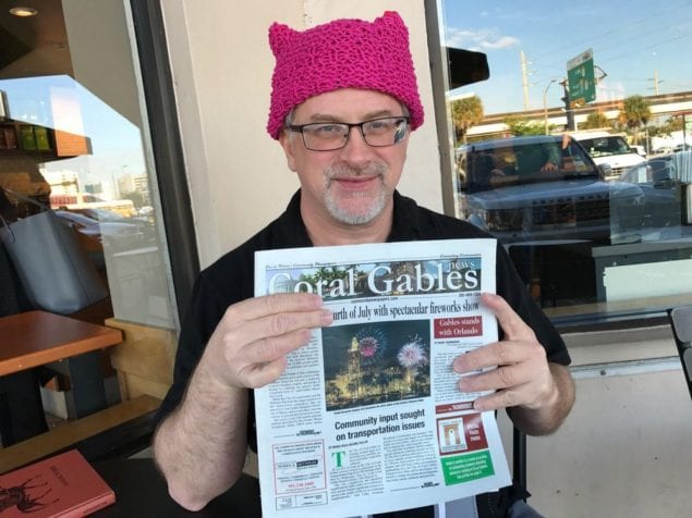 While catching up on the news one chilly morning outside the South Miami Starbucks on S. Dixie Highway (US1), Dr. Anthony Krupp of Coral Gables wears a “pussyhat” that his wife donned during the Women’s March on Washington in January. With a background in psychology and teaching, Dr. Krupp said he is thoroughly enjoying the response he gets — both positive and otherwise. The knit pink hats, topped with corners that resemble cat ears, are part of the Pussyhat Project in support of women's issues. (Photo credit: Kress Comunications)