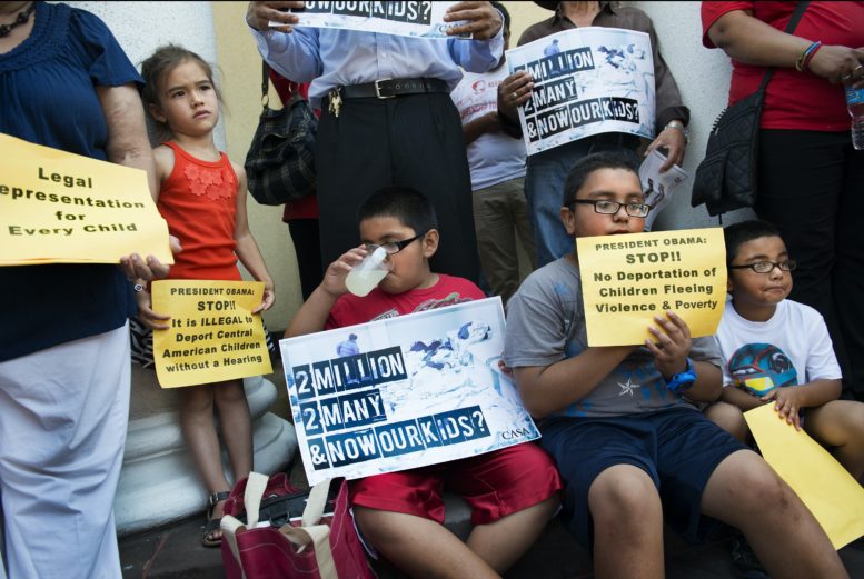 Children hold signs urging the deportation of children to end