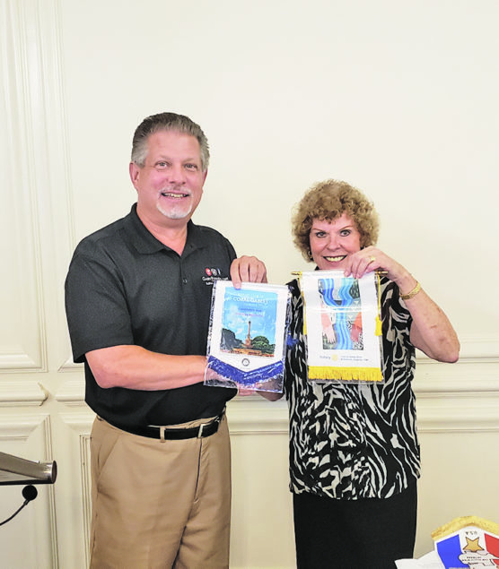 Gary Powers, Jr., author and fellow Rotarian from Virginia, is pictured exchanging club flags with Coral Gables Rotary’s Secretary and Past President, Sally Baumgartner.