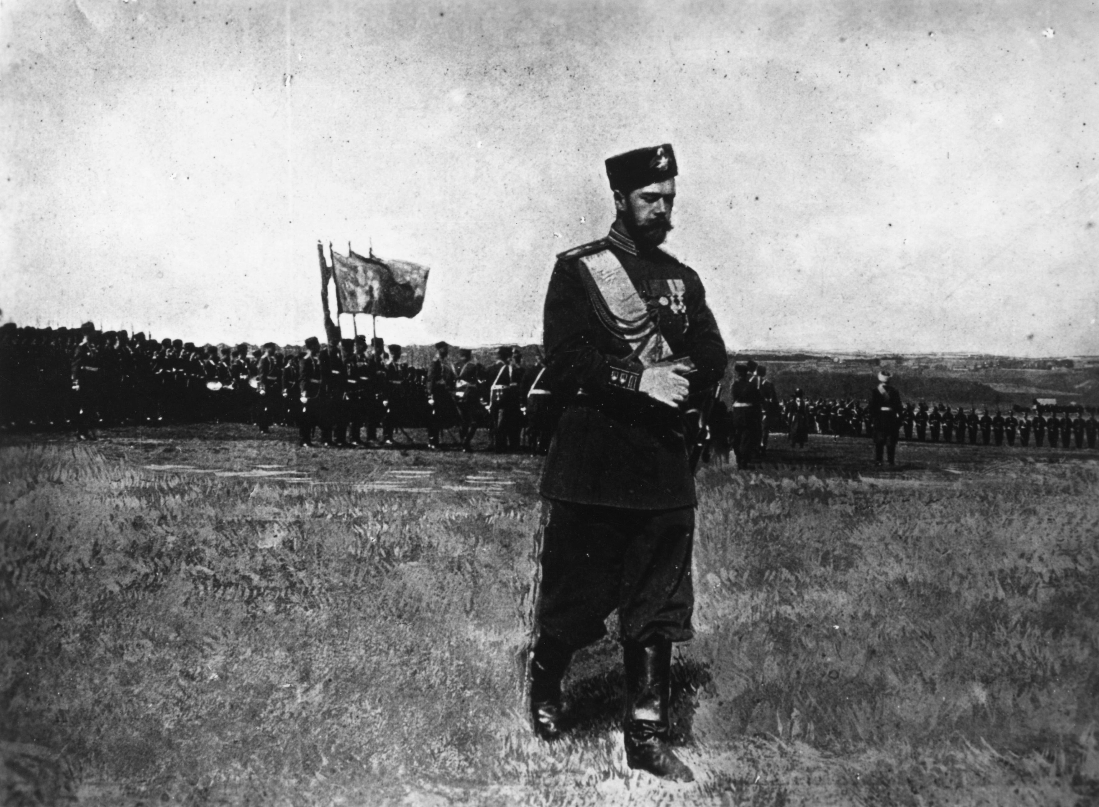 Lone man walks in field with armed forces in the background.