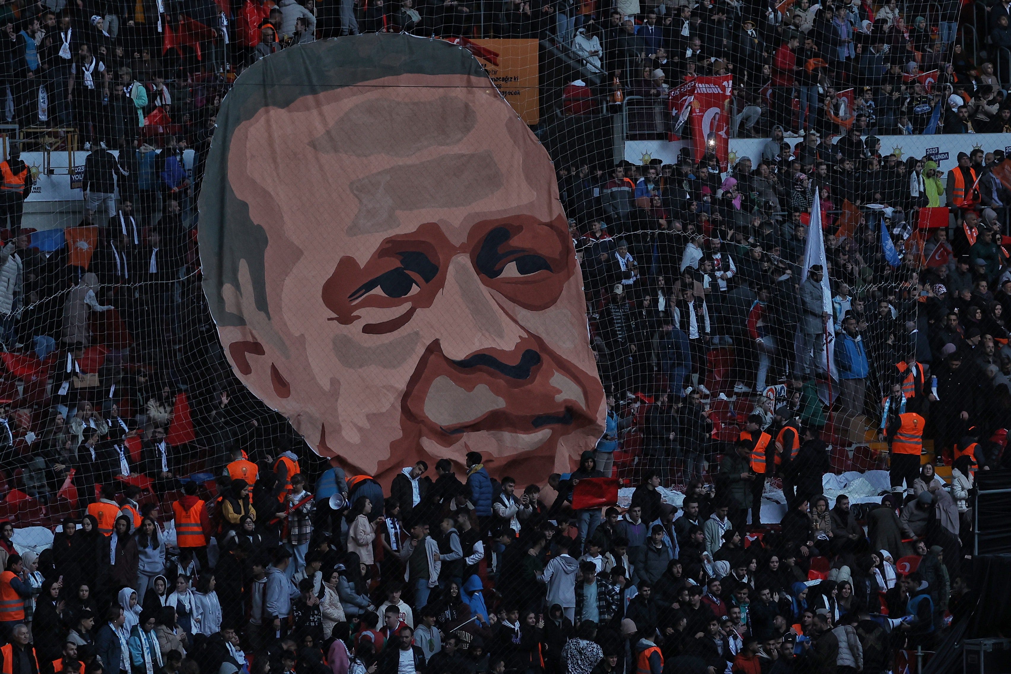 A large cut out head of a man is held aloft a crowd.