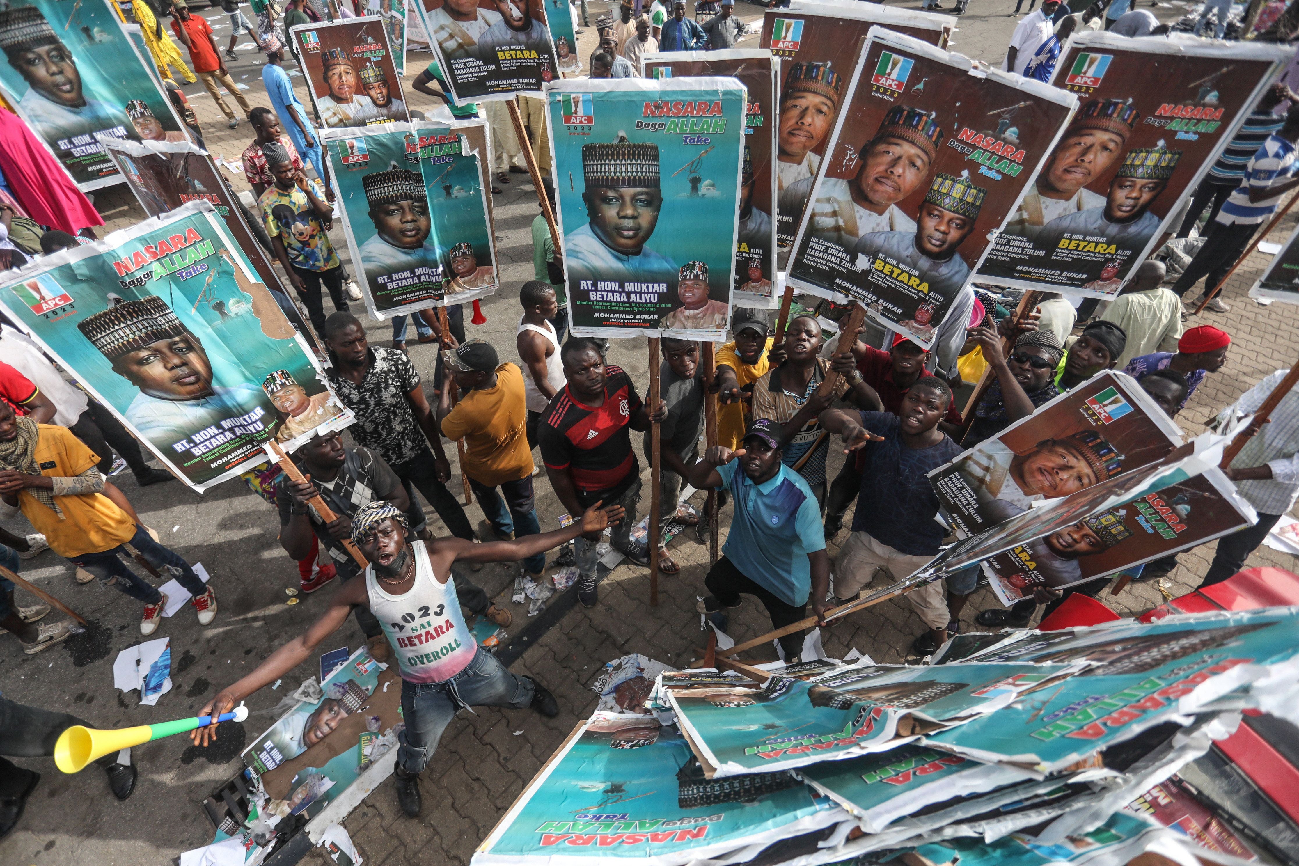 An overhead shows a group fo mainly men holding aloft placards.