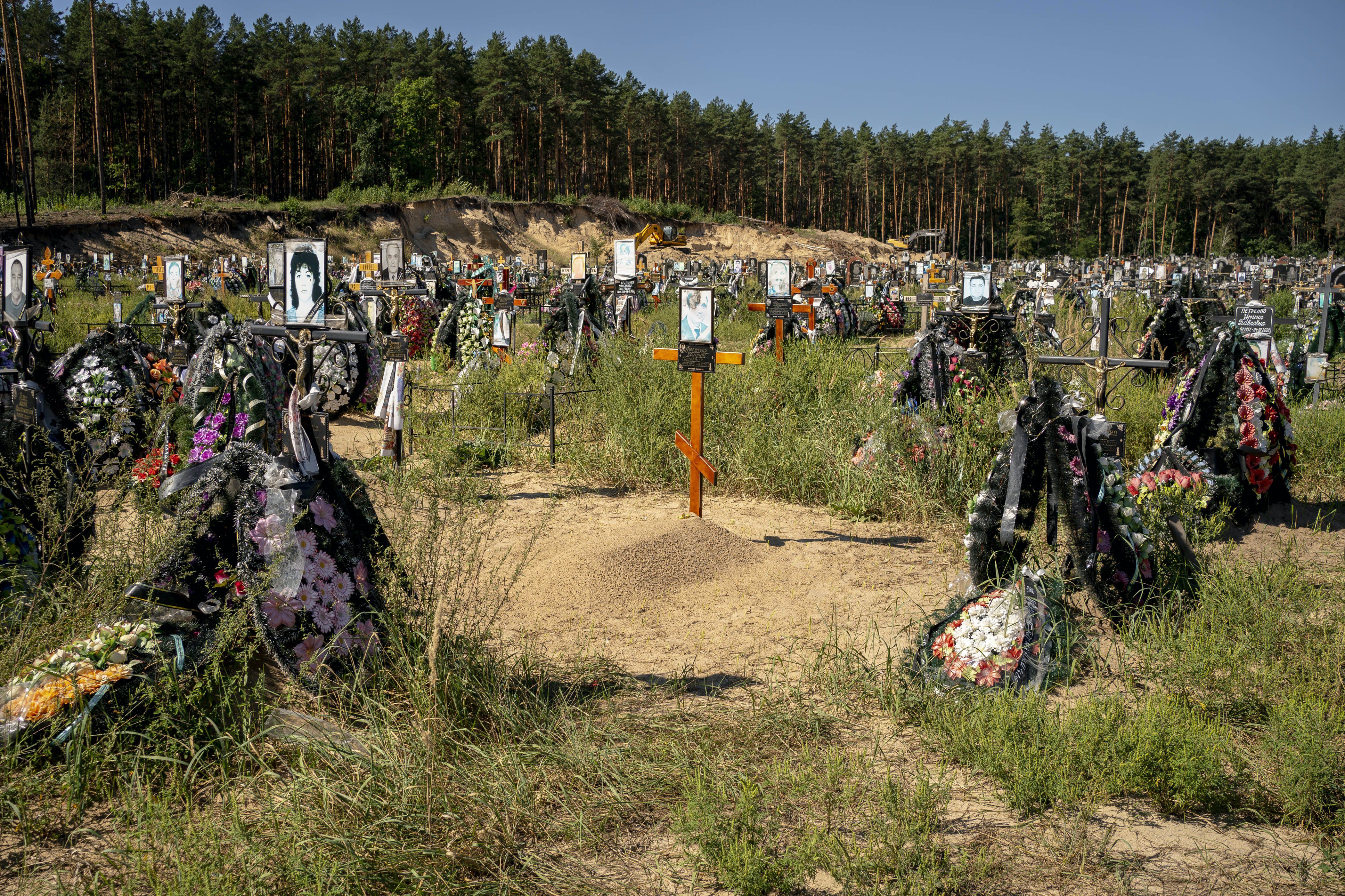 Hundreds of graves cover a patch of sand and scrub at a cemetery.