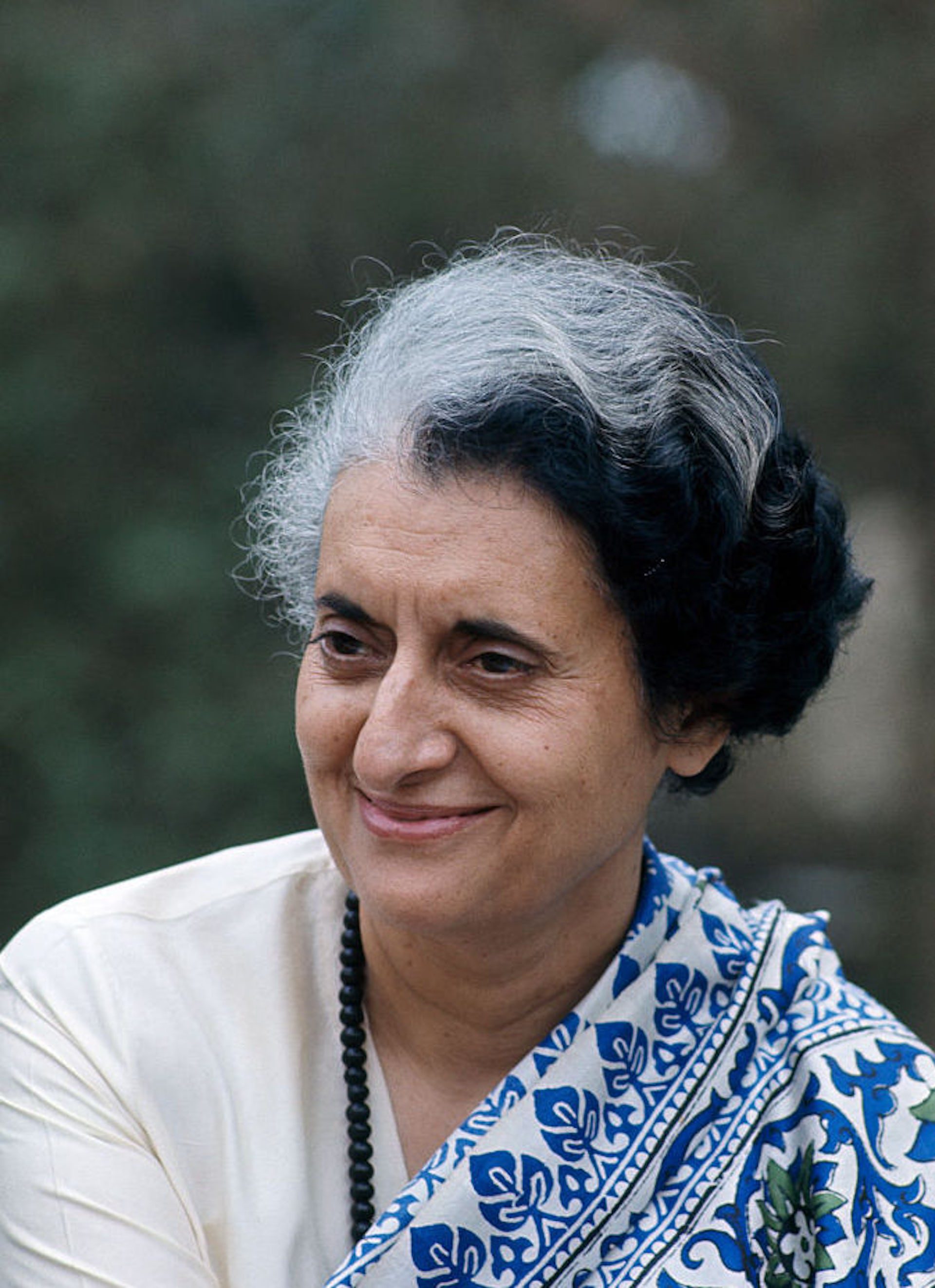 Portrait of a woman smiling, wearing a blue and white shawl.