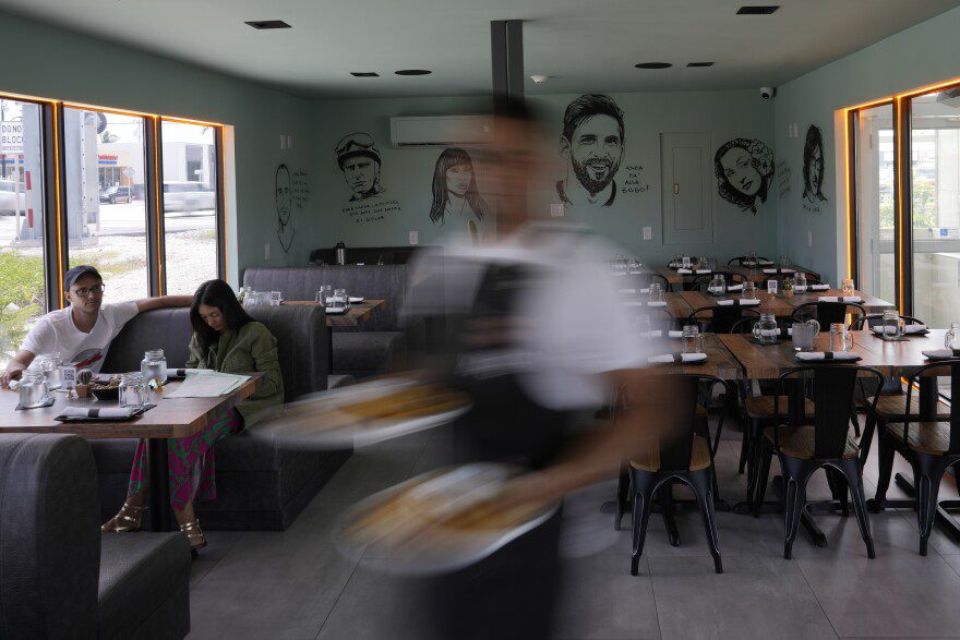 FILE - A waiter carries an order at Kao Bar & Grill in Hallandale Beach, Fla., July 10, 2023. Regional inflation in June 2025 was 3.1%, it's highest rate in a year.