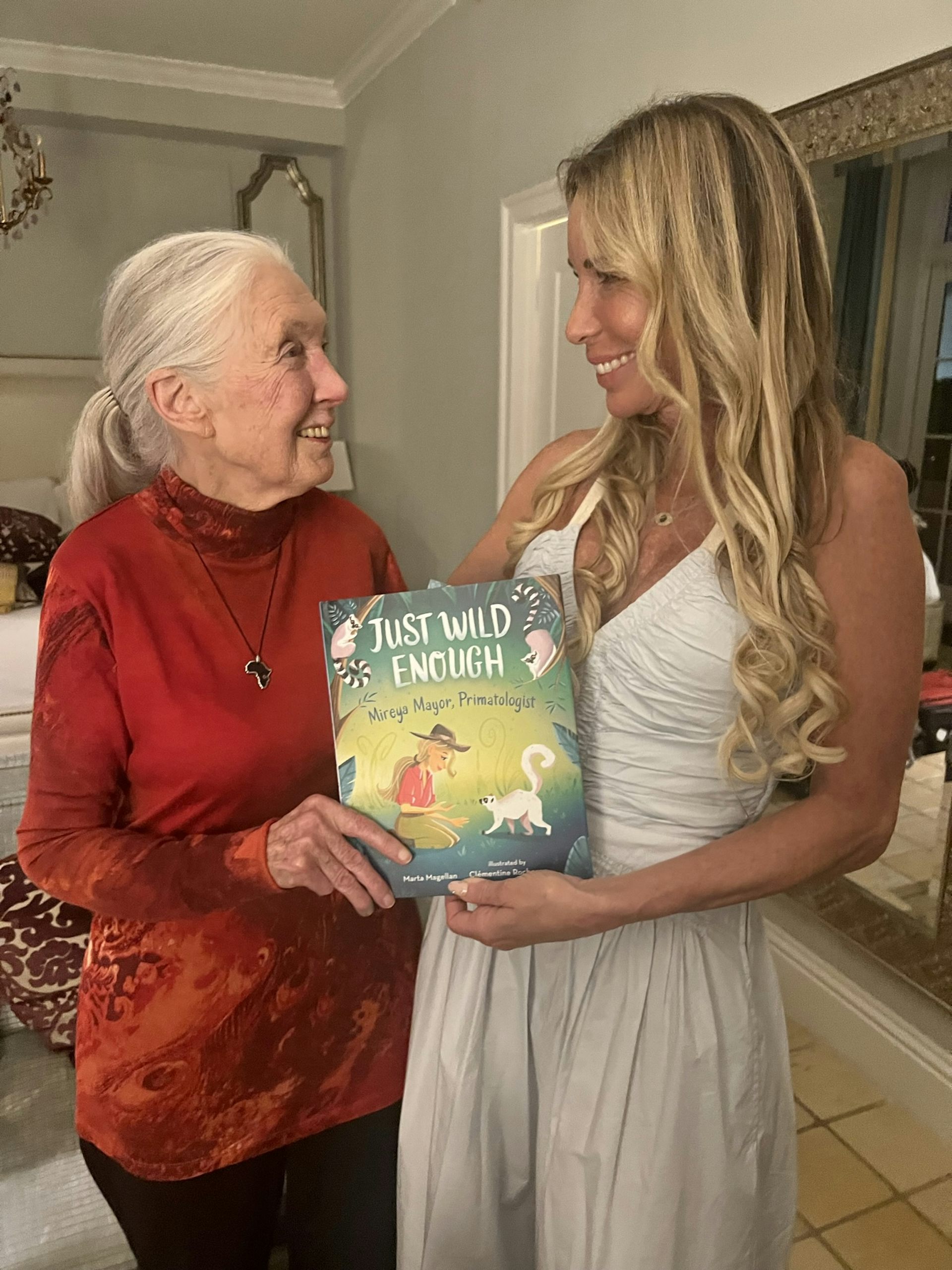 Two women face each other, smiling and holding a book