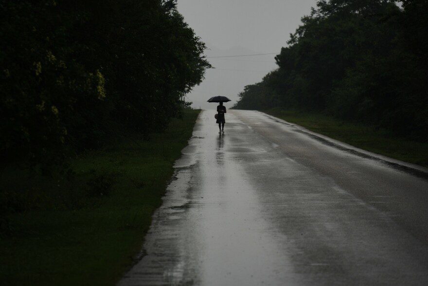 A man walks in the rain before the arrival of Hurricane Melissa in Canizo, a community in Santiago de Cuba, Tuesday, Oct. 28, 2025.