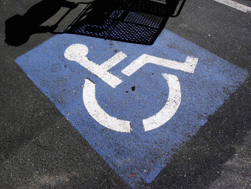 FILE - The shadow of a person with a shopping cart appears on a disability parking space in Brunswick, Maine, on Friday, April 21, 2006.